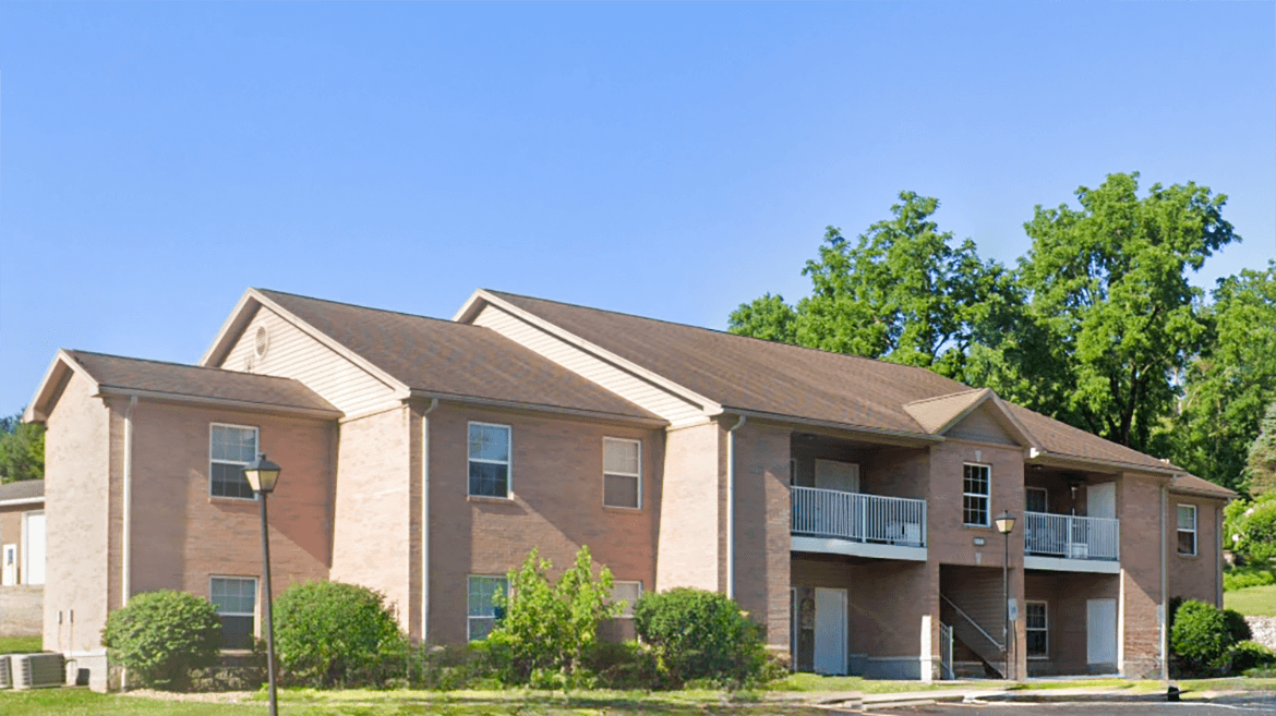 A large brick apartment building with a balcony on the second floor.