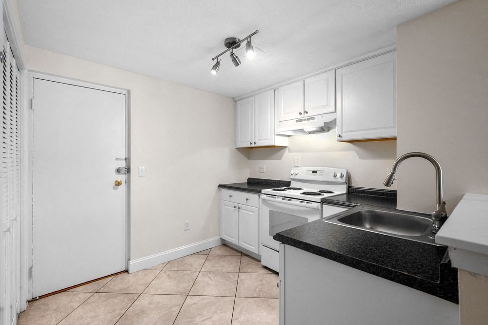 a kitchen with white appliances and black counter tops