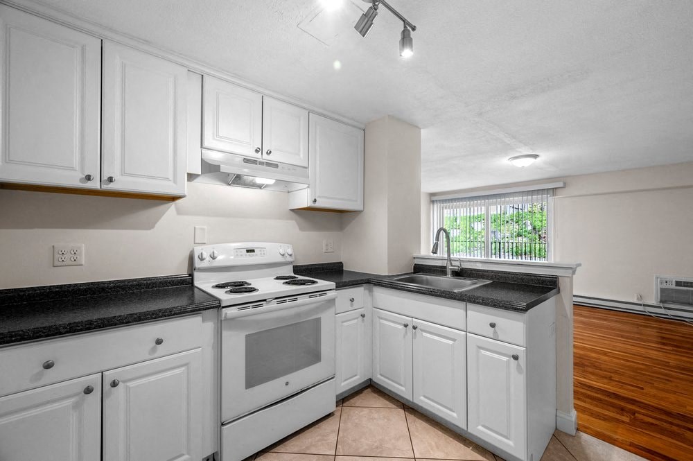 a kitchen with white cabinets and a stove and a sink