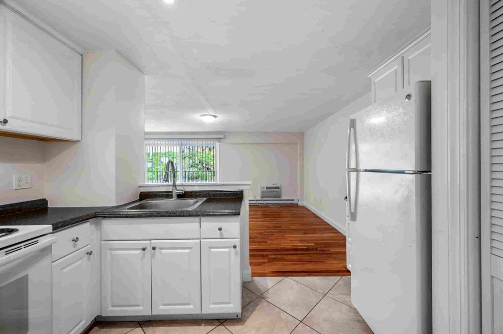 a kitchen with white cabinets and a refrigerator and a sink