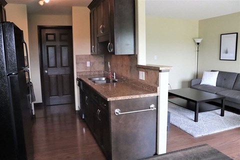A kitchen with a black refrigerator and brown cabinets.