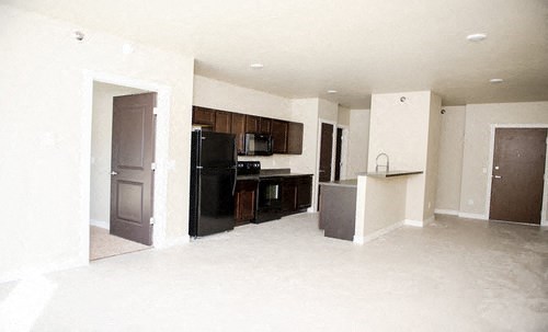 an empty kitchen with a black refrigerator and