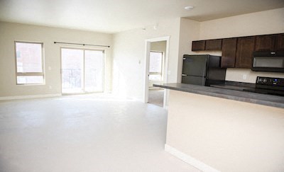 an empty living room and kitchen with a black stove and refrigerator