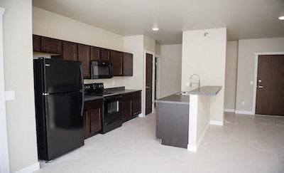 an empty kitchen with a black refrigerator and a sink