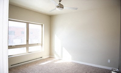 an empty room with a ceiling fan and a window