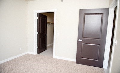 a empty room with a brown door and a closet