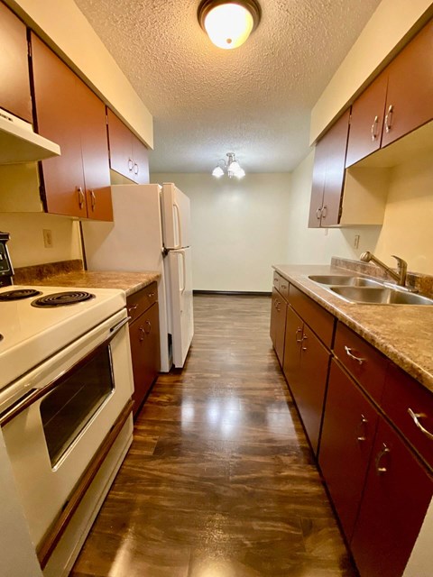 A kitchen with brown cabinets and a white refrigerator.