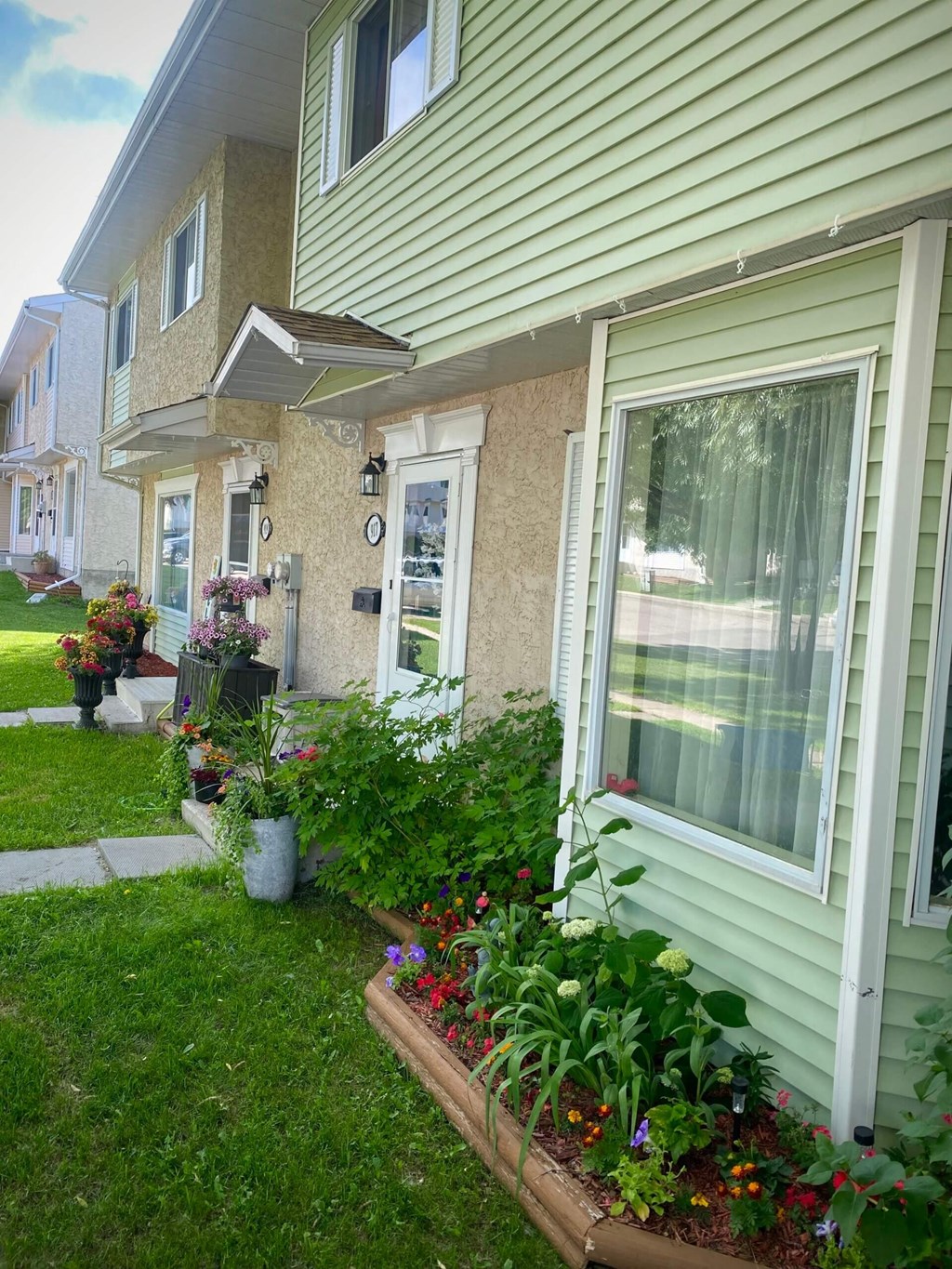 the front of a house with flowers in the yard