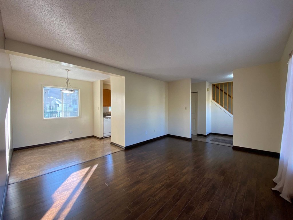 the living room and dining room of an empty house with wood flooring