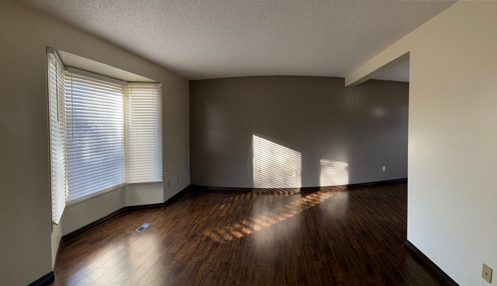 an empty living room with wood floors and window blinds