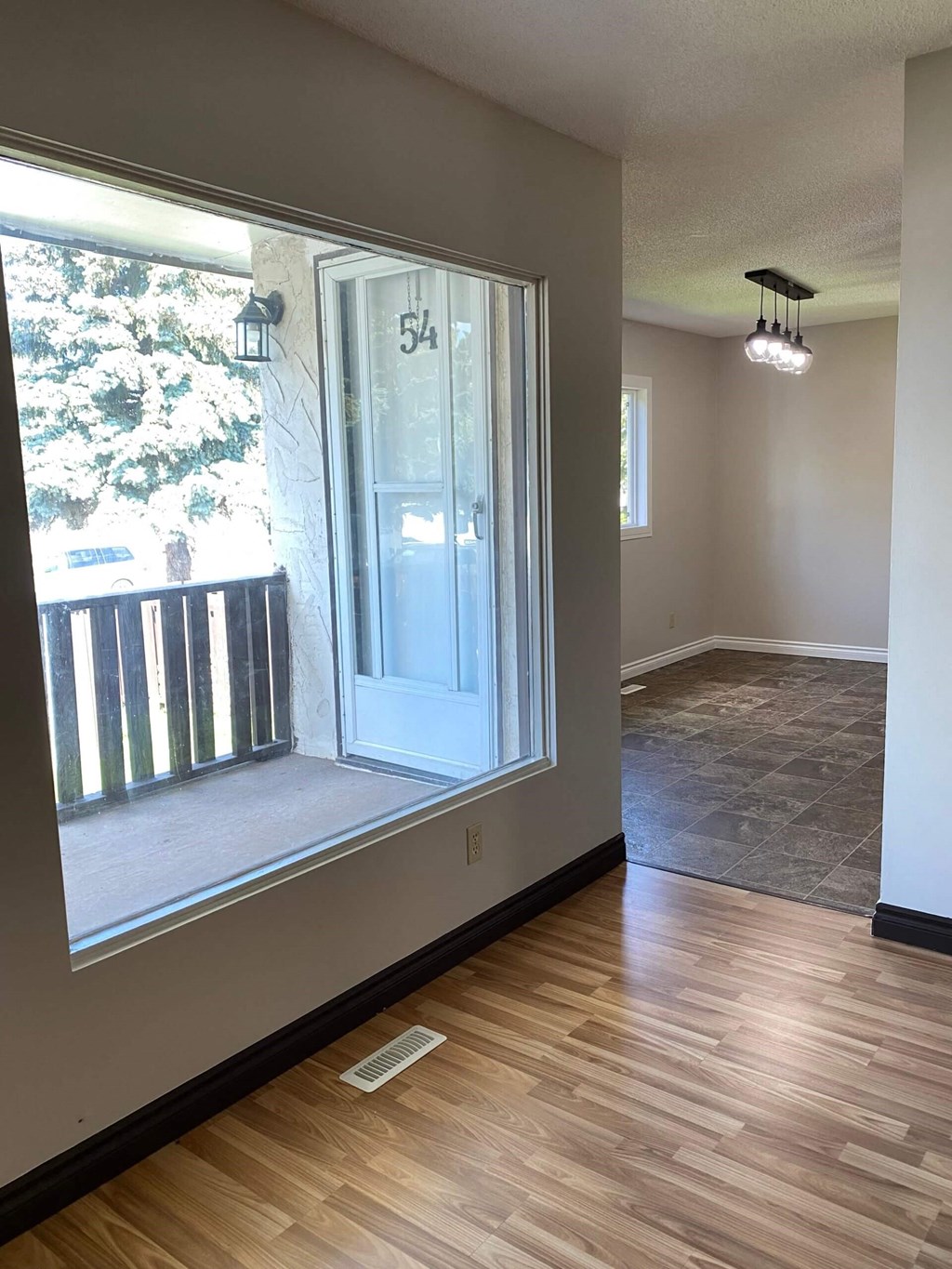 an empty house with a large window and a door to a porch