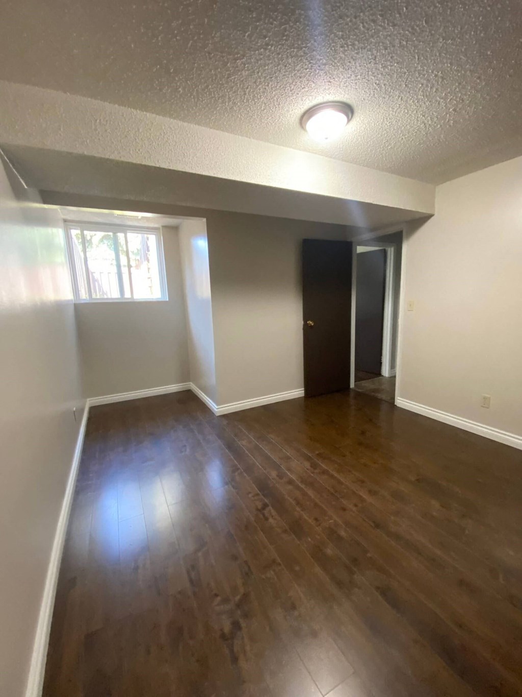 an empty living room with wood floors and a window