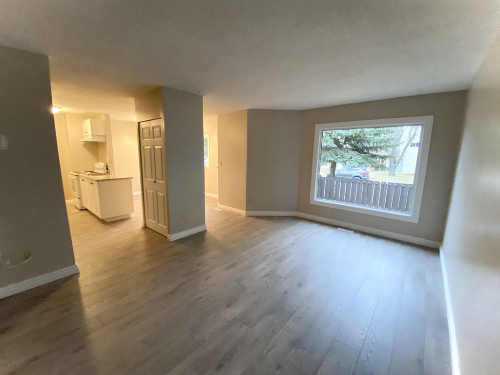 an empty living room with wooden floors and a large window