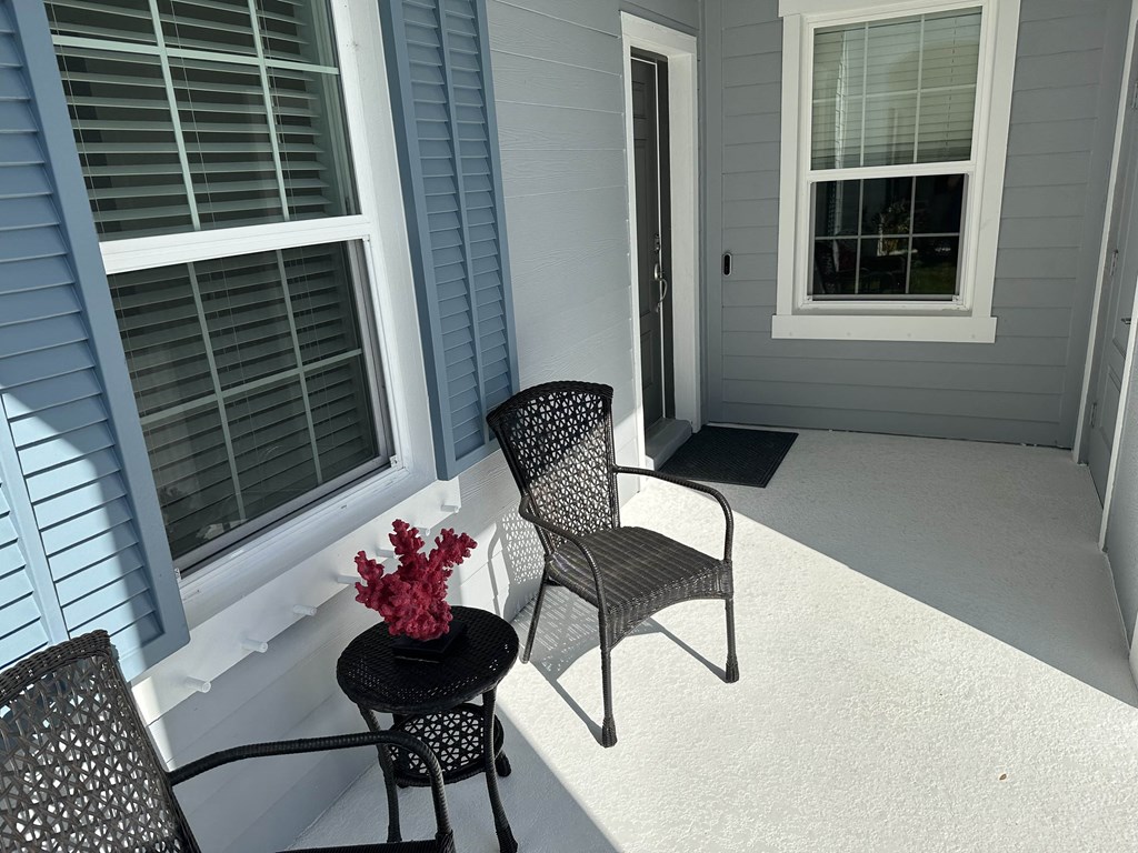 a patio with two chairs and a table with flowers on it