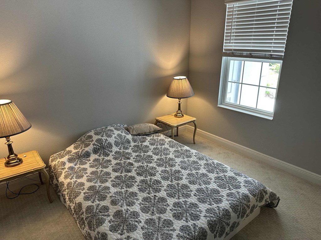 a bedroom with a bed and two lamps and a window