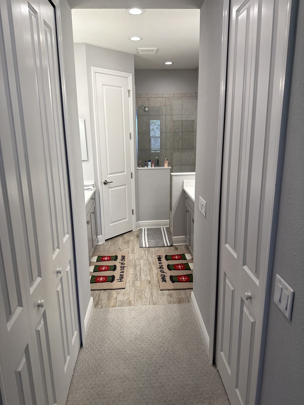 a look down the hallway of a bathroom with a tub and shower and rugs