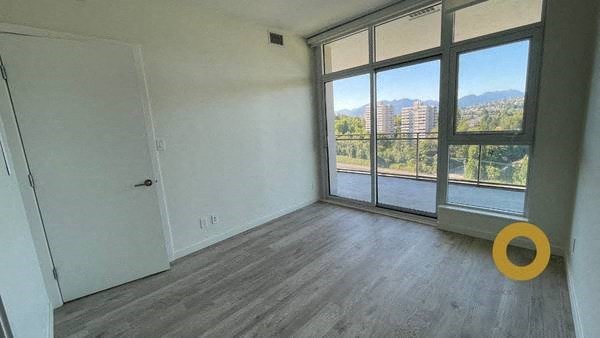 an empty living room with a large window and wooden floors
