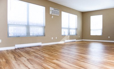 an empty living room with a hard wood floor and large windows