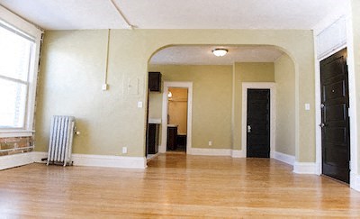 an empty living room with a wood floor and a radiator