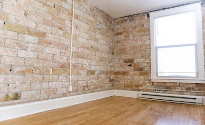 an empty room with an exposed brick wall and wooden floors
