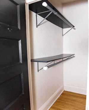 a closet with shelves on the wall and a black door