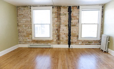 an empty room with a wood floor and exposed brick wall