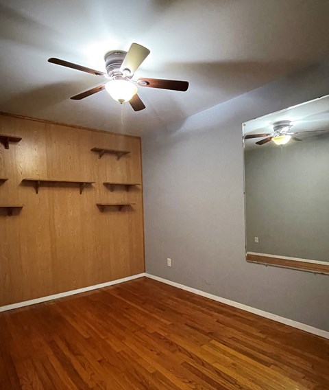 a bedroom with a wood floor and a ceiling fan