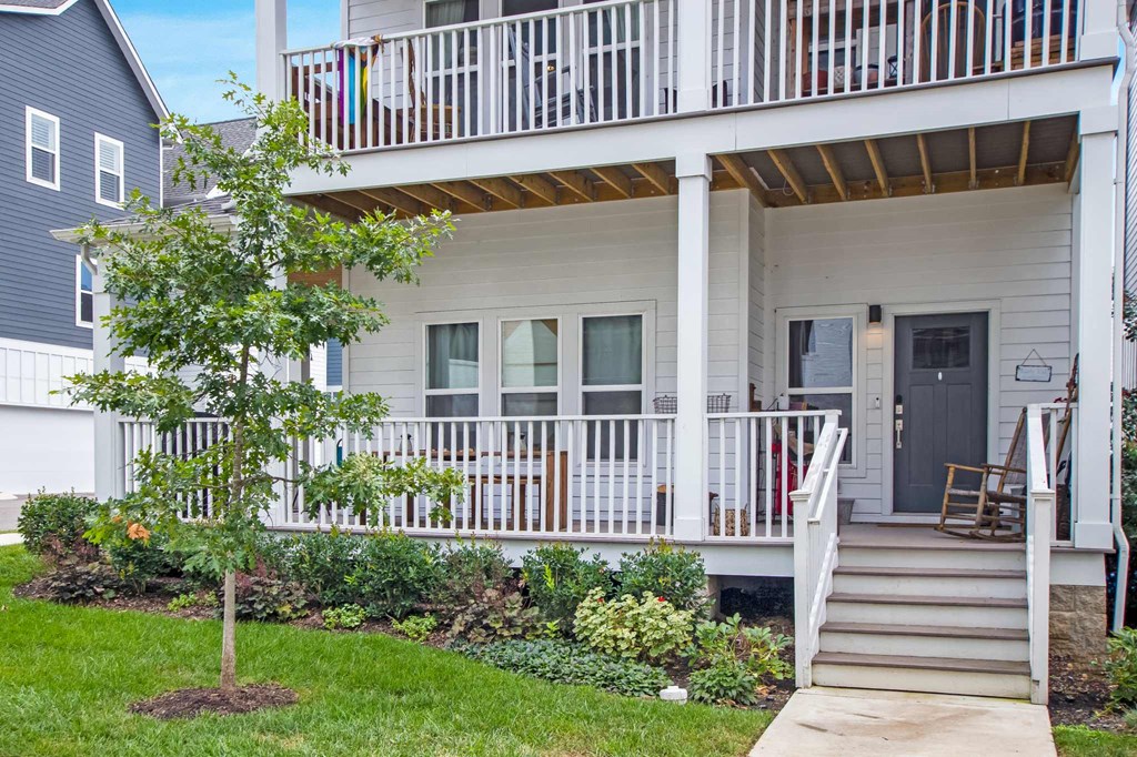 the front of a white house with stairs and a porch