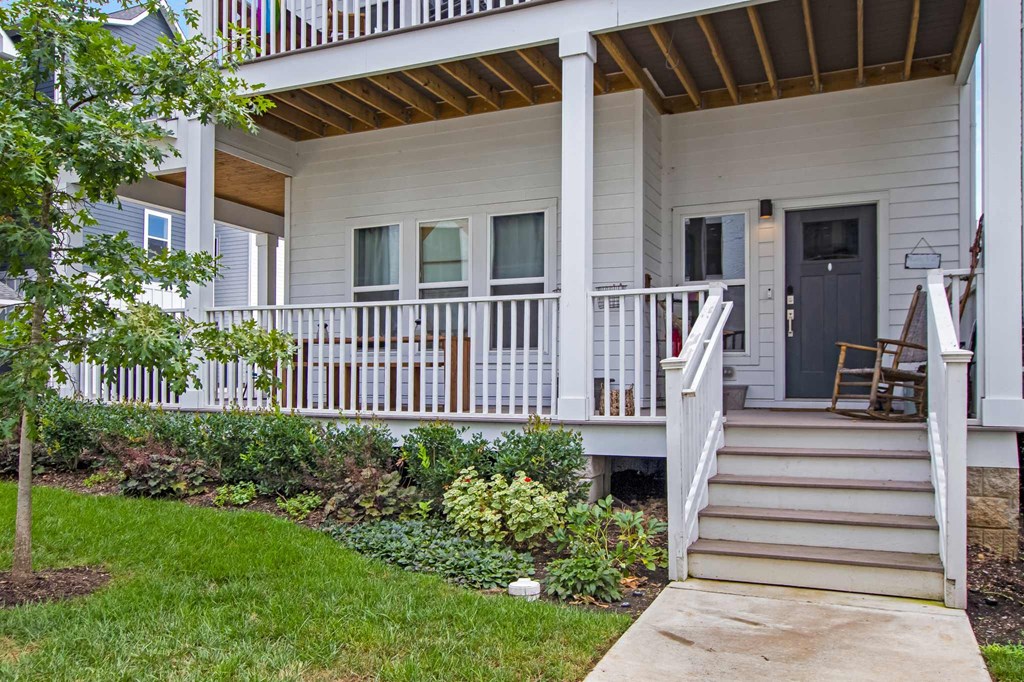 the front of a white house with stairs and a porch