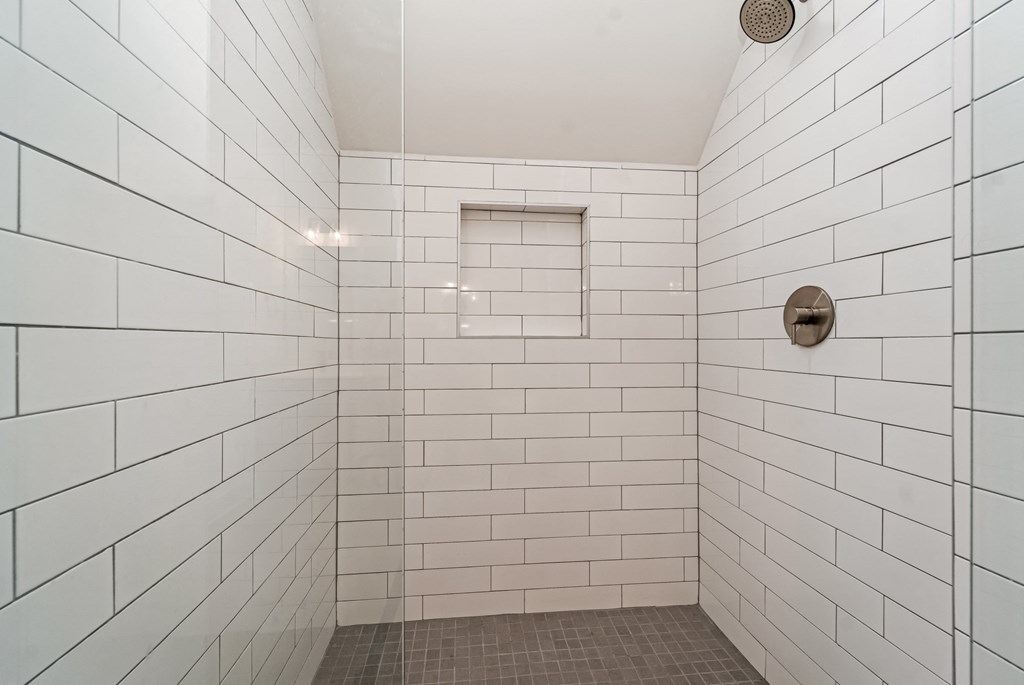 a white tiled shower in a bathroom with white subway tiles
