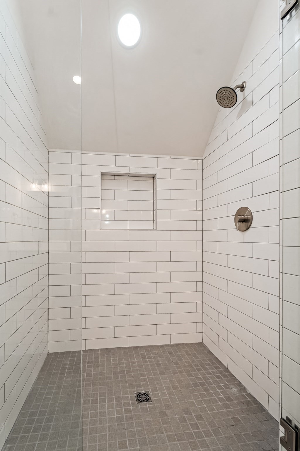 a white tiled shower in a bathroom with a shower head