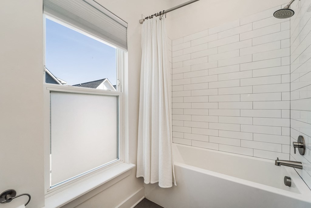 a white bathroom with a window and a shower curtain