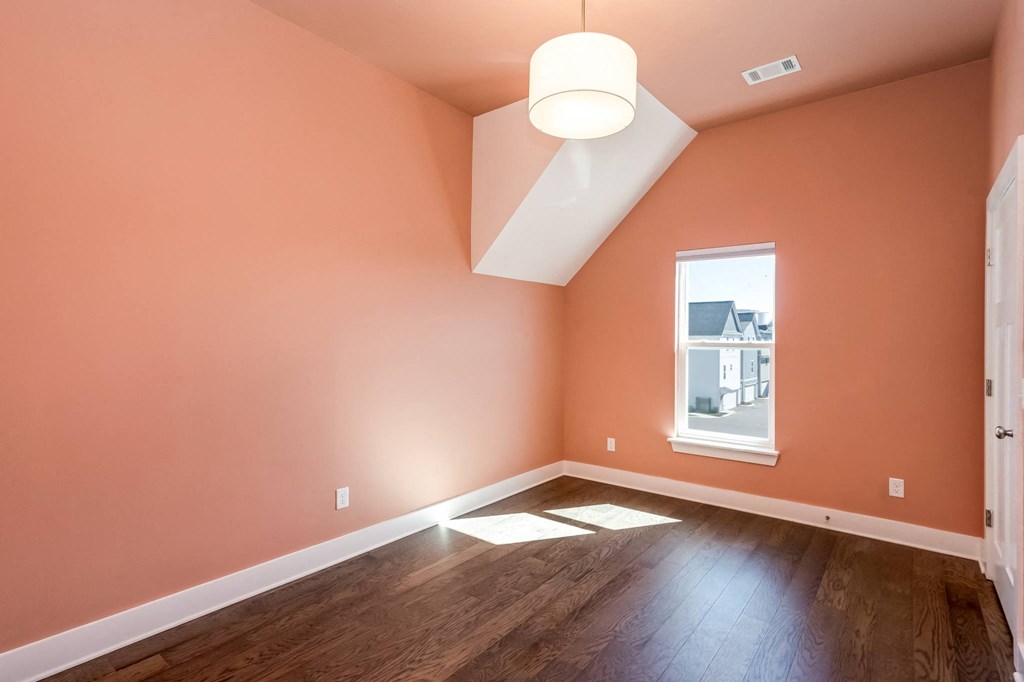 an empty room with pink walls and a window and wood floors