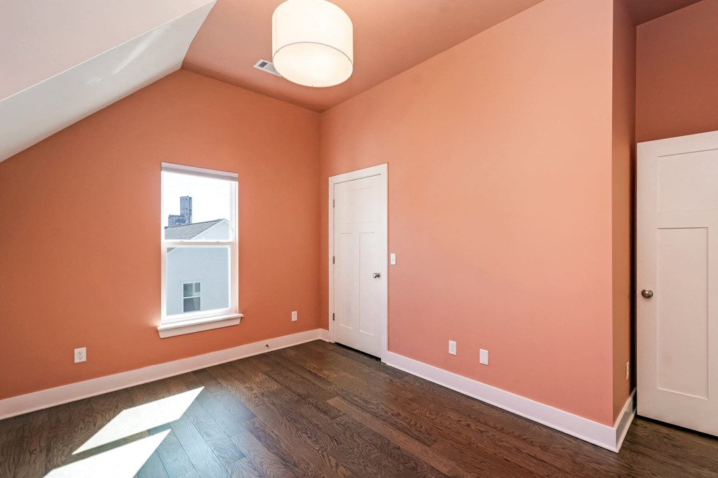 an empty room with pink walls and a white door and a window