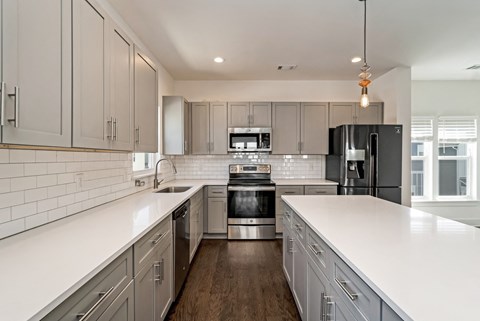 a large kitchen with white counters and stainless steel appliances