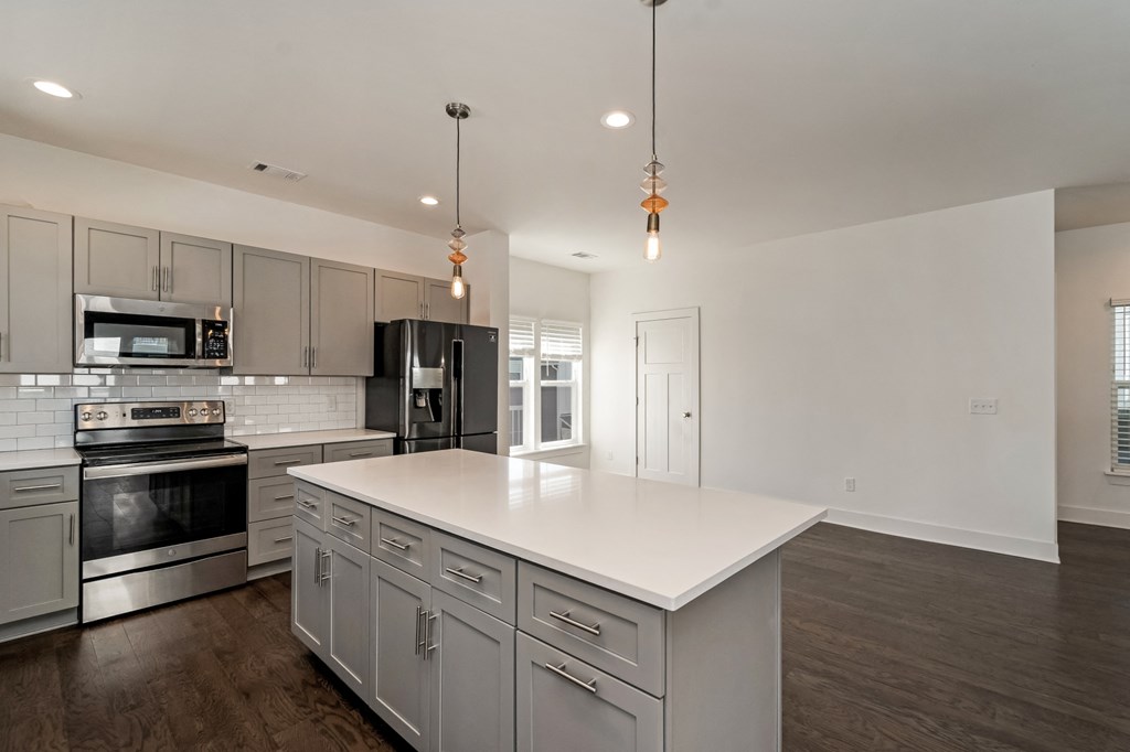 an open kitchen with a large white island and stainless steel appliances
