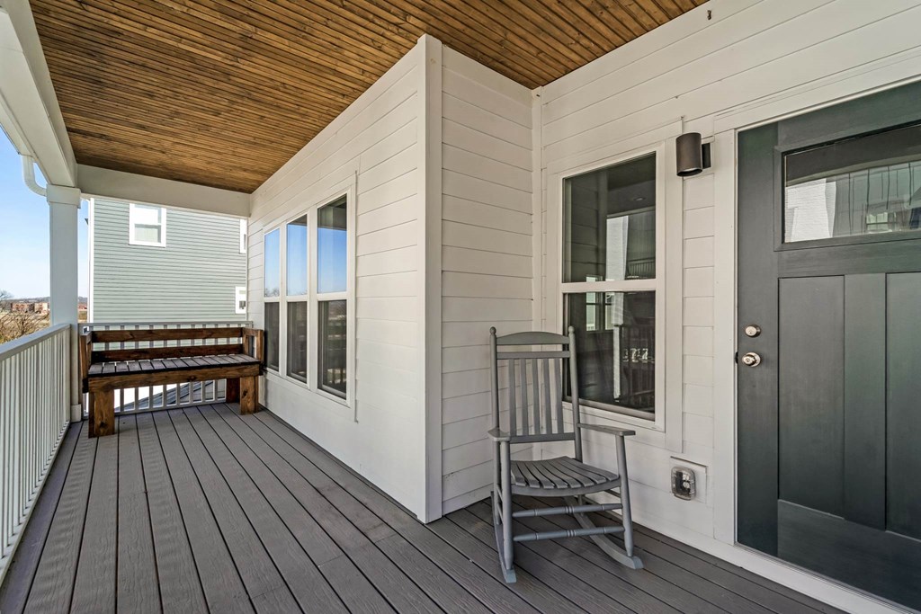 a front porch with a rocking chair and a black door