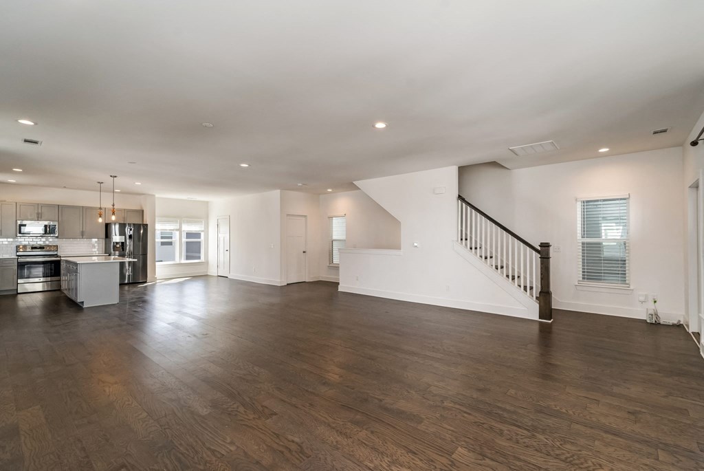 the living room and kitchen of a new home with white walls and wood floors