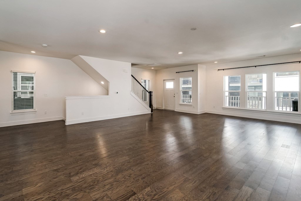 an empty living room with wood floors and white walls and a staircase