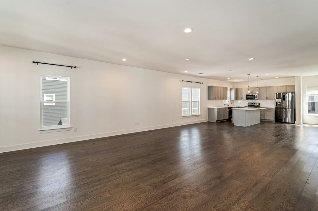 the living room and kitchen of a new home with white walls and wood floors