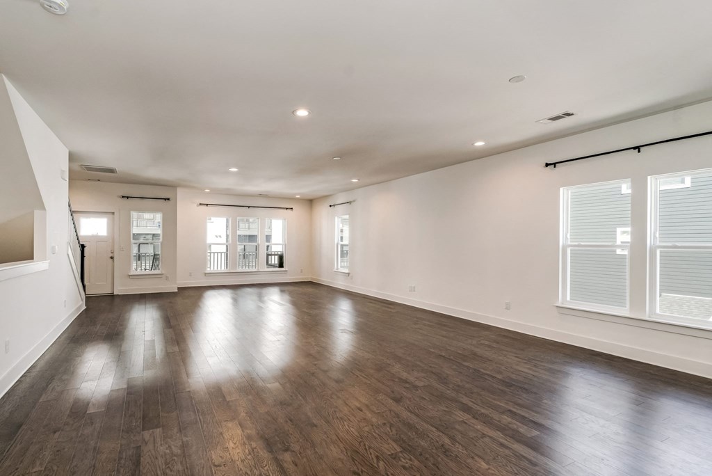 an empty living room with wood floors and white walls