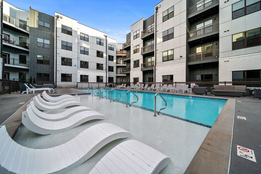 an apartment building with a swimming pool and lounge chairs