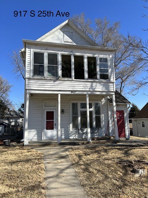A white two-story house with a red door and windows is located at 917 S 25th Ave.