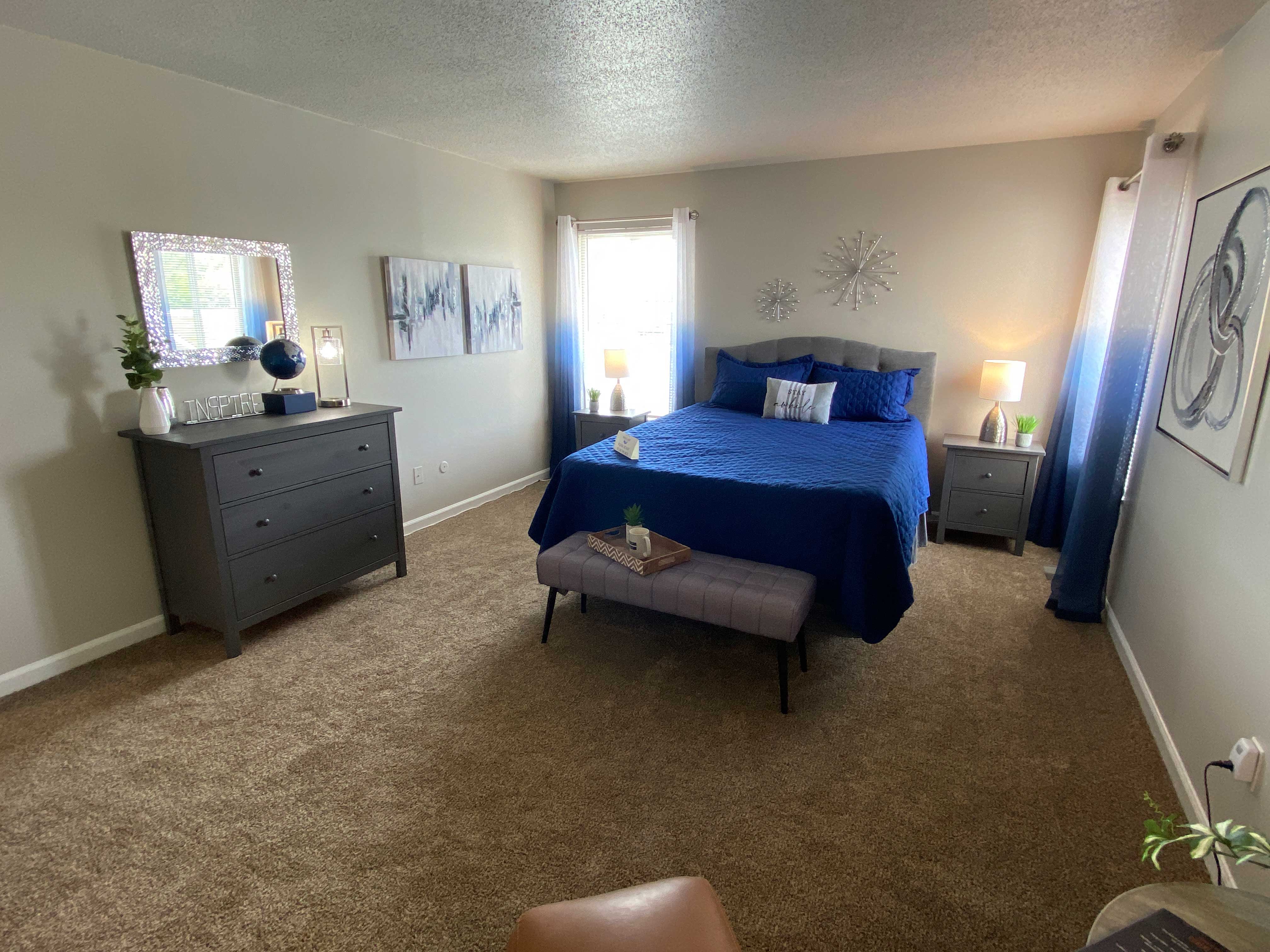 A bedroom with a blue bed and a brown chair.