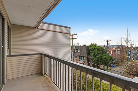 A balcony with a metal railing and a view of a residential area.