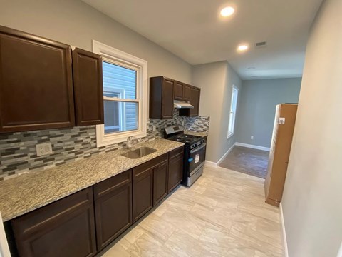 A kitchen with brown cabinets and a stone countertop.
