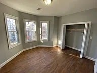 A room with wood floors and three windows.