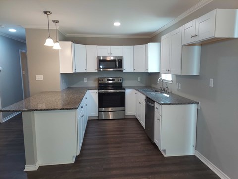 A kitchen with white cabinets and a granite countertop.