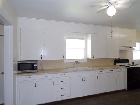 A kitchen with white cabinets and a microwave on the counter.