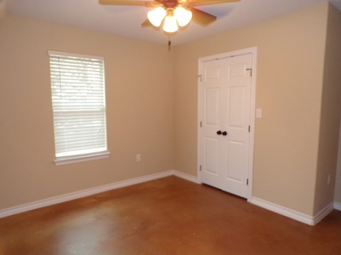 an empty living room with a ceiling fan and a white door